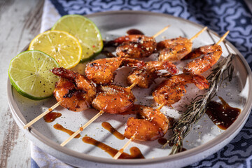 A plate with homemade fried shrimp skewers with garlic, lemon and herbs, selective focus