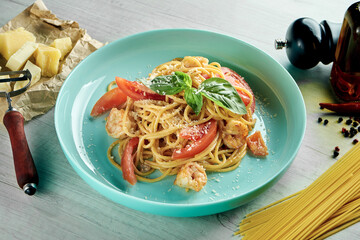 Italian spaghetti pasta with white sauce, shrimps and parmesan cheese served in a blue plate on a wooden background. Restaurant food. Seafood