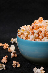Cheese popcorn in blue bowl on black background
