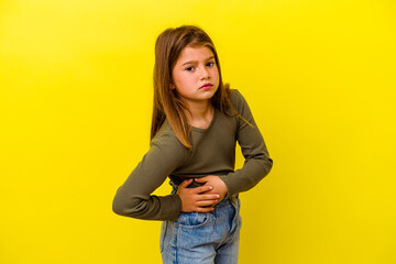 Little caucasian girl isolated on yellow background having a liver pain, stomach ache.