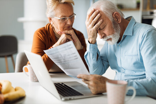 Frustrated senior couple sitting at home and checking their home finances