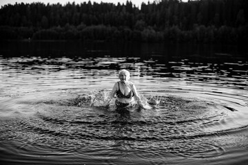 Old woman in the river at summer. Black and white photo.