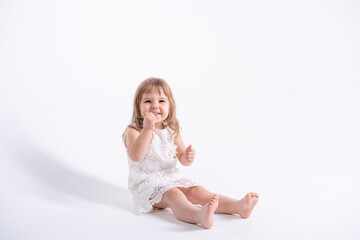 beautiful little girl in white dress sitting on white background