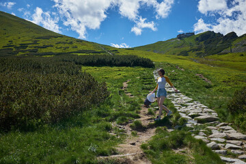 Scenic panoramic view of mountains landscape with a woman on a trail