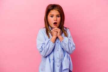 Little caucasian girl isolated on pink background  praying for luck, amazed and opening mouth...