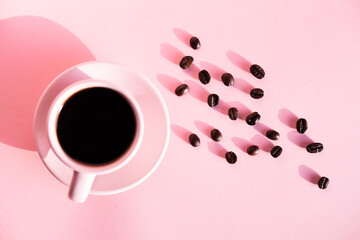Pink cup of coffee with pink background and coffee beans