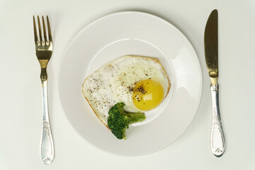 On a white background, a plate with a fried egg