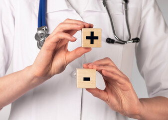 Plus and minus signs on wooden cubes. Medical concept