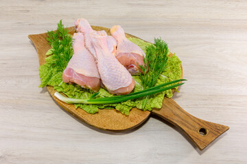 Raw, greasy, chicken thighs on a lettuce leaf. Board for cutting chicken. Preparing chicken legs...