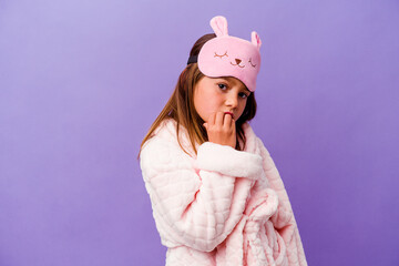 Little caucasian girl wearing pajama isolated on purple background biting fingernails, nervous and very anxious.