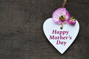 Happy Mother's Day greeting card with spring flowers and decorative heart on old wooden background. 