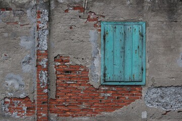 Teal color window on a ruined brick wall.