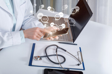 Doctor is in the office at the table is in correspondence on the phone.