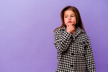 Little caucasian girl isolated on purple background Little caucasian girl isolated on purple background looking sideways with doubtful and skeptical expression.