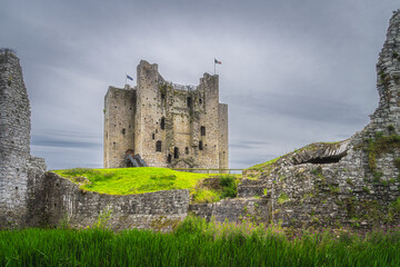 Fototapeta na wymiar View on Trim Castle through a gap between fortification walls with dark moody sky in Trim village, County Meath, Ireland