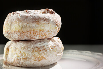 Two donuts stacked on white plate and black background