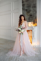  A bride in a white interior in a beautiful boudoir dress. Beautiful classic fireplace behind her