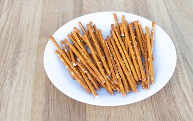 Dry sticks with salt in a plate on wooden background