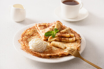 Russian traditional breakfast for Shrovetide of thin pancakes with whipped cream on white.