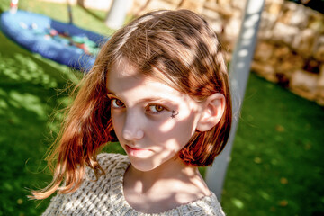 portrait of beautiful teenage girl with loose hair with shodow on face on the city children's playground on sunny day