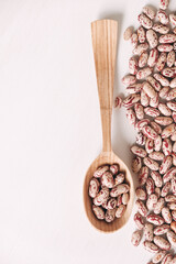 Raw dry beans in a wooden spoon scattered on a white background. Top view. Copy, empty space for text