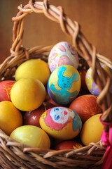 Fototapeta na wymiar Easter wooden basket filled with colorful painted eggs on the eve of Easter. Warm background. Vertical photo.