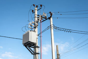 High voltage transformer mounted on a pole on blue sky background at sunny day