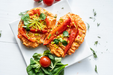 vegan roasted red pepper dip sandwich spread on freshly baked bread slice with salad garnish on white porcelain plate 