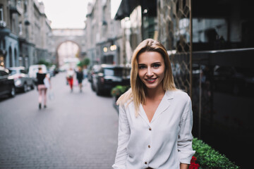 Fototapeta premium Happy young woman enjoying summer evening standing beside building on street