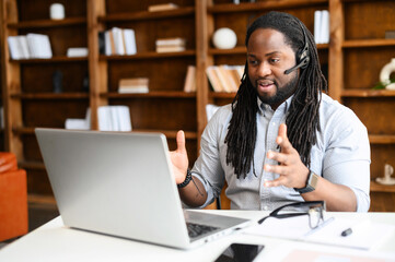 Diverse office employees concept. A focused African-American man with a dreadlocks wearing wireless...