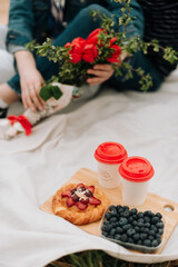 A picnic on the grass, a bouquet of flowers, blueberries and a sweet bun