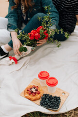 girl with a bouquet of flowers sits on a white plaid, summer picnic