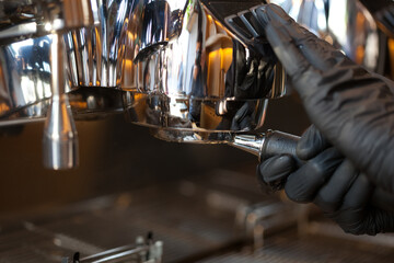 barista hands inserting bottomless holder into professional espresso coffee machine