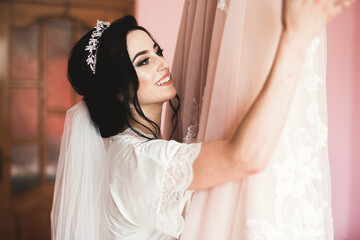 Fototapeta premium Gorgeous bride in robe posing and preparing for the wedding ceremony face in a room