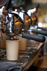 modern professional espresso machine with coffee pouring into take away paper cup