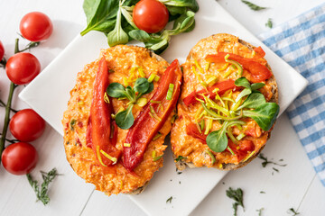 vegan roasted red pepper dip sandwich spread on freshly baked bread slice with salad garnish on white porcelain plate 