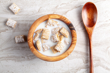 A simple breakfast concept with a bowl of frosted bite size wheat cereal in milk on marble kitchen...