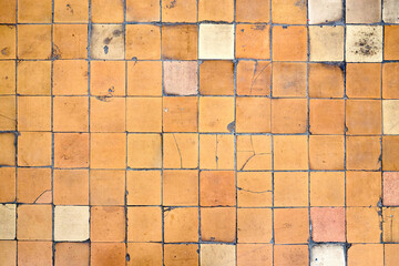 Orange brown white beige old shabby worn out floor tiles with damages cracks dirt caverns potholes and paint stains. Art design background texture.