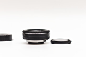 Untitled small black 24mm lens for DSLR camera lying on white background