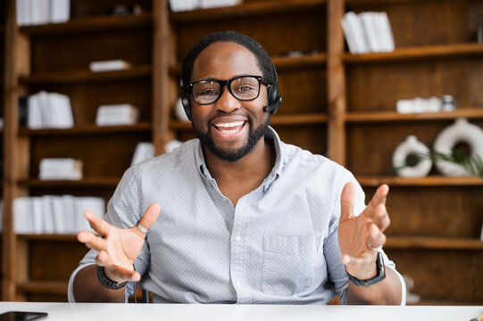 Video conference with a cheerful male colleague, headshot of smiling African man wearing headset, talking online, holding video meeting or webinar, video chat with male teacher or tutor online