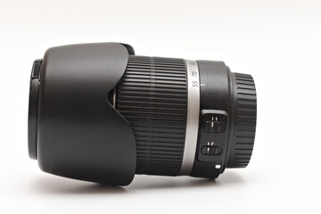 Large black zoom lens for DSLR camera with lens hood lying on white background