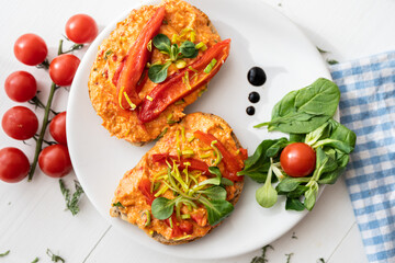 vegan roasted red pepper dip sandwich spread on freshly baked bread slice with salad garnish on white porcelain plate 