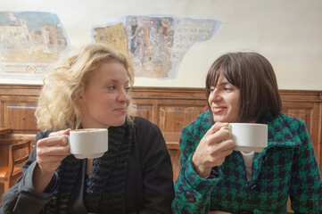Duegiovani donne amiche bevono un cappuccino al bar