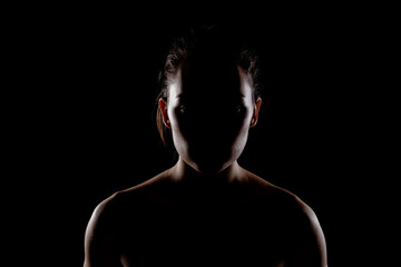 silhouette portrait of a beautiful young woman against dark backgroung.