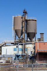 Vertical exterior of a brick and metal industrial building with storage silos, a dust collection...