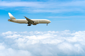 side image commercial passenger aircraft or cargo transportation airplane flying over white fluffy cloud with blue sky in bright day and spread the wheel prepare landing to airport