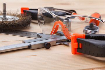 Safety glasses and various tools on a wooden table.