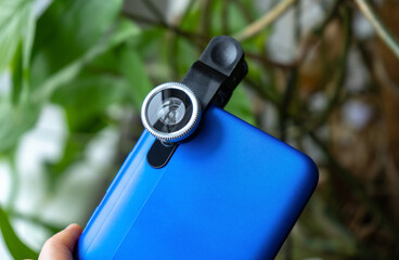 Overhead phone lens with clips on the blue modern smartphone. Extra macro camera for mobile device