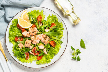 Green Salad with baked salmon fish. Top view at white table.