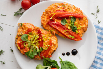 vegan roasted red pepper dip sandwich spread on freshly baked bread slice with salad garnish on white porcelain plate 
